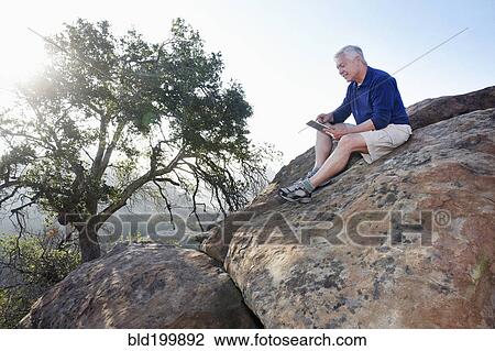 Caucasian man using digital tablet in remote area View Large Photo Image Stock Image - Caucasian man using digital tablet in remote area. Fotosearch