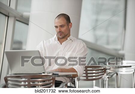 Stock Image - Caucasian man using laptop in cafe. Fotosearch