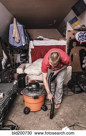 Stock Image - Caucasian man vacuuming floor. Fotosearch