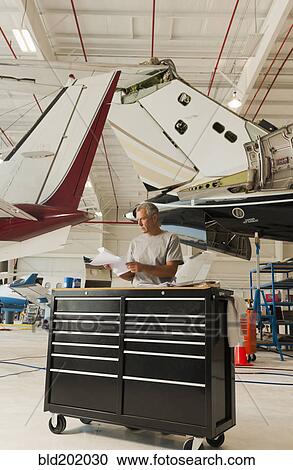 Caucasian man working in airplane hangar View Large Photo Image Stock Image - Caucasian man working in airplane hangar. Fotosearch