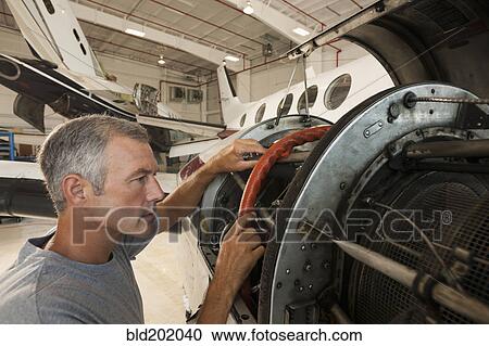 Caucasian man working in airplane hangar View Large Photo Image Stock Image - Caucasian man working in airplane hangar. Fotosearch