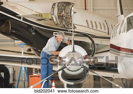 Caucasian man working in airplane hangar View Large Photo Image Stock Image - Caucasian man working in airplane hangar. Fotosearch