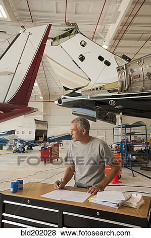 Caucasian man working in airplane hangar View Large Photo Image Stock Photo - Caucasian man working in airplane hangar. Fotosearch