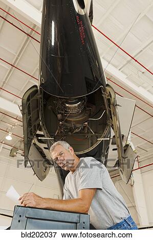 Caucasian man working in airplane hangar View Large Photo Image Stock Photo - Caucasian man working in airplane hangar. Fotosearch
