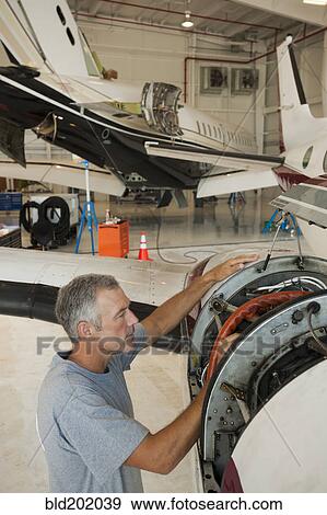 Stock Photo - Caucasian man working in airplane hangar. Fotosearch