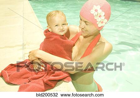 Stock Image - Caucasian mother and baby at poolside. Fotosearch