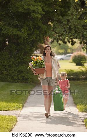 Stock Image - Caucasian mother and daughter returning with groceries. Fotosearch