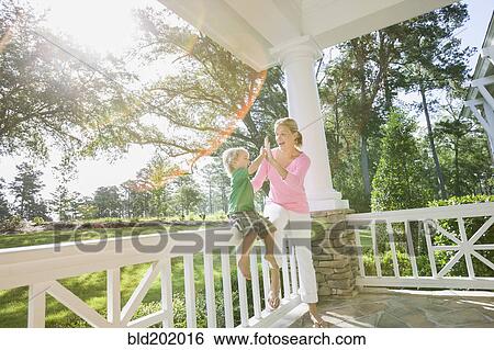 Stock Photograph - Caucasian mother and son playing on porch together. Fotosearch