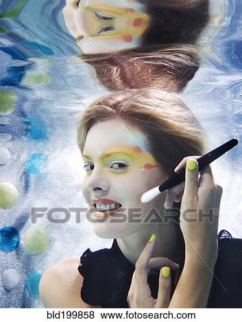 Stock Photo - Caucasian putting makeup on under water. Fotosearch