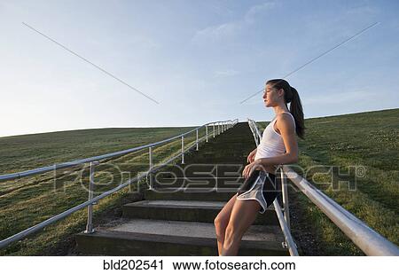 Stock Image - Caucasian runner leaning on staircase railing. Fotosearch