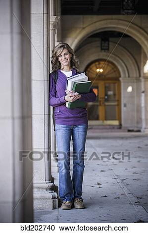 Stock Image - Caucasian student carrying books on campus. Fotosearch