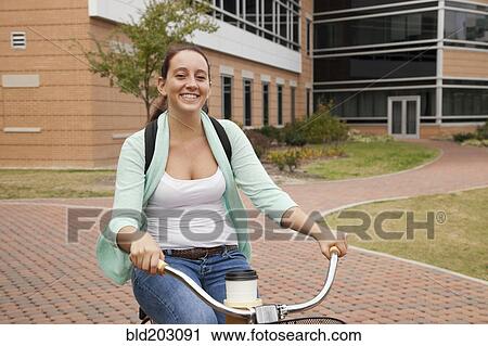Stock Image - Caucasian student riding bicycle on campus. Fotosearch