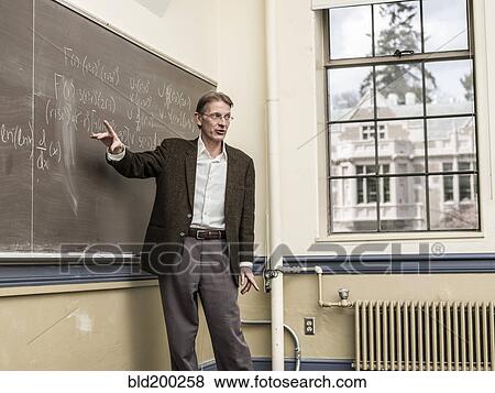 Stock Photo - Caucasian teacher writing on blackboard. Fotosearch