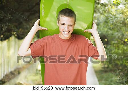 Caucasian teenage boy smiling and holding surfboard View Large Photo Image Stock Image - Caucasian teenage boy smiling and holding surfboard. Fotosearch