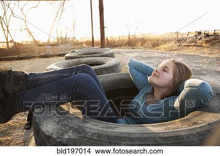 Picture - Caucasian teenager sitting in large tire. Fotosearch