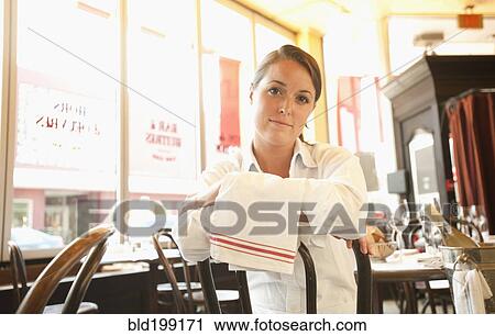 Stock Image - Caucasian waitress sitting in restaurant. Fotosearch
