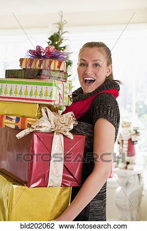 Stock Image - Caucasian woman carrying Christmas gifts. Fotosearch