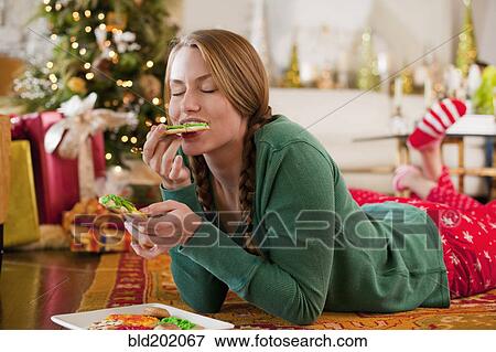 Stock Photo - Caucasian woman eating Christmas cookies. Fotosearch