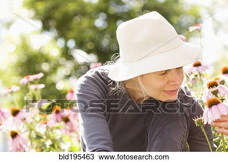 Stock Image - Caucasian woman examining flowers. Fotosearch