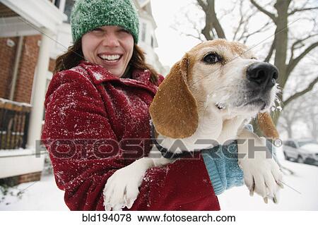 Stock Photo - Caucasian woman holding dog in snow. Fotosearch