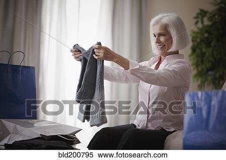 Stock Photography - Caucasian woman holding new sweater. Fotosearch