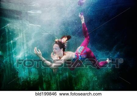 Stock Photograph - Caucasian woman in clothing swimming under water. Fotosearch