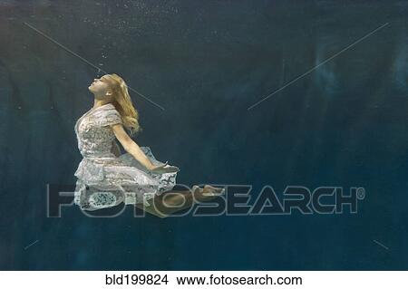 Picture - Caucasian woman in dress swimming under water. Fotosearch