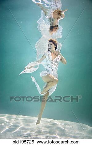 Stock Photography - Caucasian woman in elegant dress under water. Fotosearch