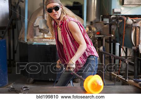 Stock Image - Caucasian woman in glass blowing studio. Fotosearch