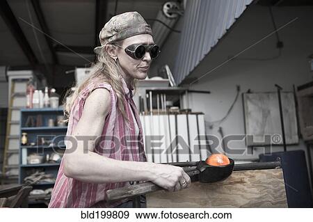 Stock Photo - Caucasian woman in glass blowing studio. Fotosearch