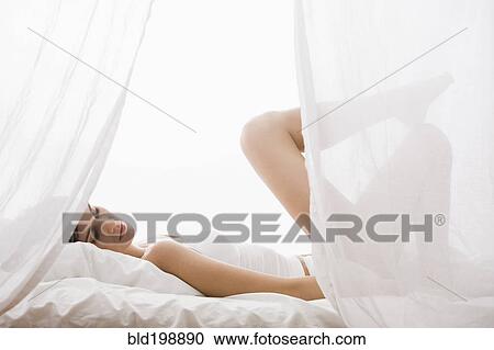 Stock Image - Caucasian woman laying in bed. Fotosearch