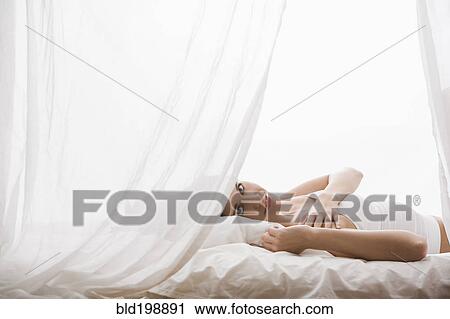 Stock Image - Caucasian woman laying in bed. Fotosearch