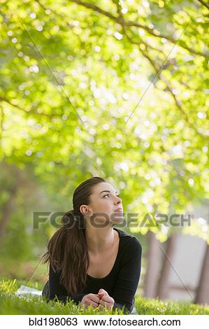 Caucasian woman laying in grass in park View Large Photo Image Stock Image - Caucasian woman laying in grass in park. Fotosearch