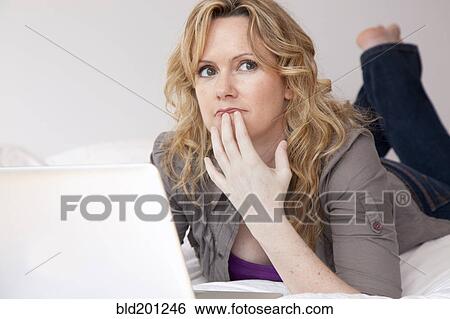 Caucasian woman laying on bed using laptop View Large Photo Image Stock Photograph - Caucasian woman laying on bed using laptop. Fotosearch