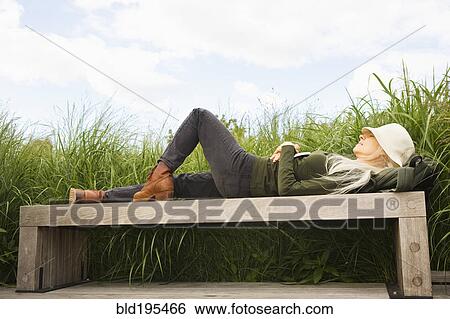 Stock Photograph - Caucasian woman laying on bench. Fotosearch