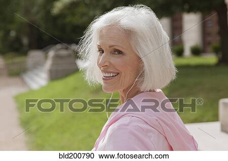 Stock Image - Caucasian woman listening to mp3 player. Fotosearch