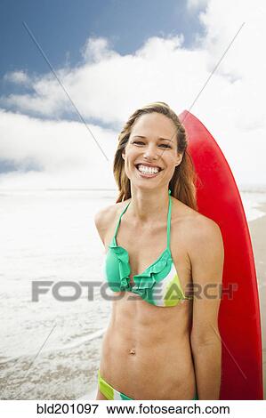Stock Photo - Caucasian woman on beach with surfboard. Fotosearch
