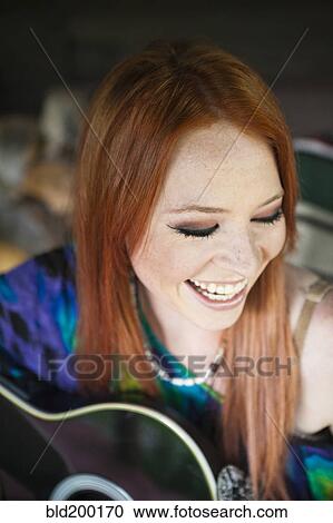 Stock Image - Caucasian woman playing guitar. Fotosearch