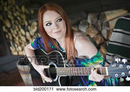 Stock Image - Caucasian woman playing guitar. Fotosearch