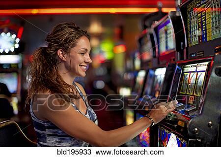 Stock Image - Caucasian woman playing slot machine in casino. Fotosearch