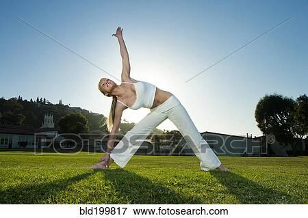 Stock Photo - Caucasian woman practicing yoga in field. Fotosearch