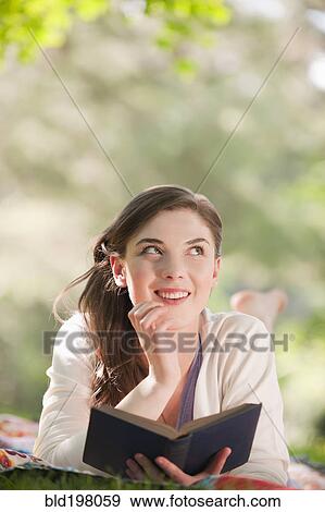 Stock Photo - Caucasian woman reading book outdoors. Fotosearch