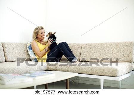 Stock Photo - Caucasian woman relaxing on sofa with dog. Fotosearch