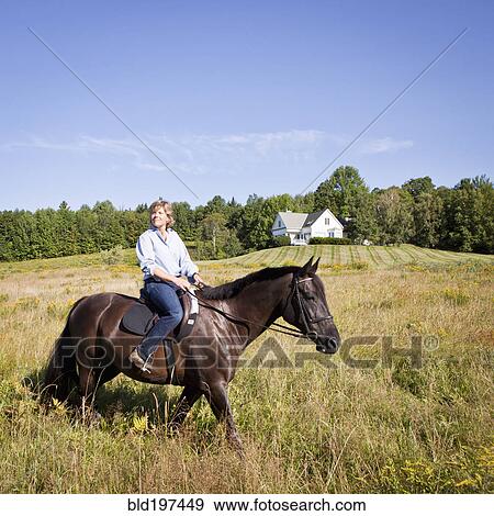 Stock Photo - Caucasian woman riding horse in field. Fotosearch