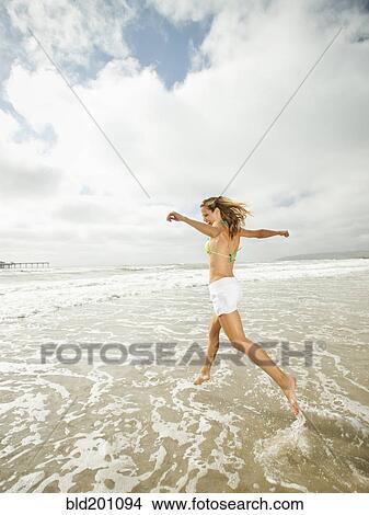 Caucasian woman running in ocean View Large Photo Image Picture - Caucasian woman running in ocean. Fotosearch
