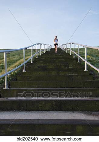 Stock Image - Caucasian woman running up steps. Fotosearch
