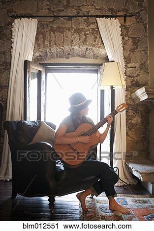 Caucasian woman sitting in chair playing guitar View Large Photo Image Stock Image - Caucasian woman sitting in chair playing guitar. Fotosearch