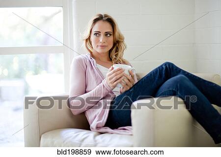 Stock Photo - Caucasian woman sitting in chair drinking coffee. Fotosearch