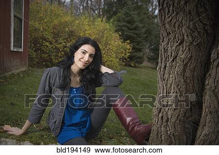 Caucasian woman sitting in yard near tree View Large Photo Image Stock Photo - Caucasian woman sitting in yard near tree. Fotosearch