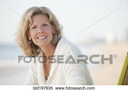 Stock Photography - Caucasian woman sitting on beach. Fotosearch